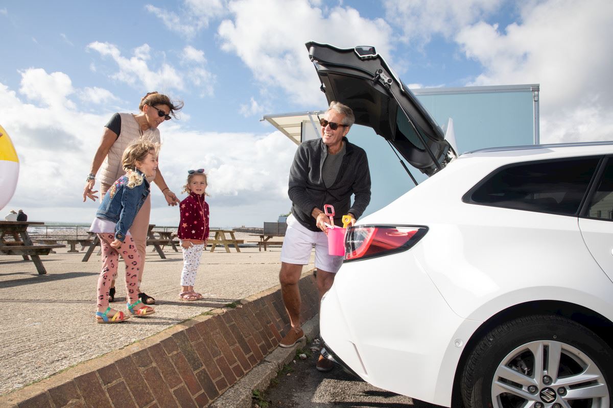 A family getting things out of a car boot at the beach