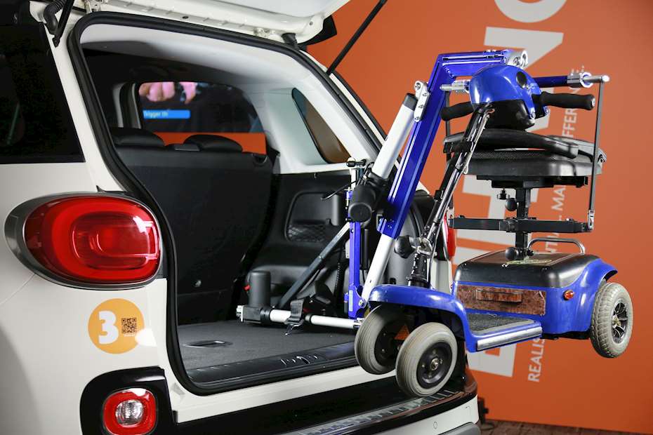 A foldable mobility scooter attached to a car boot hoist