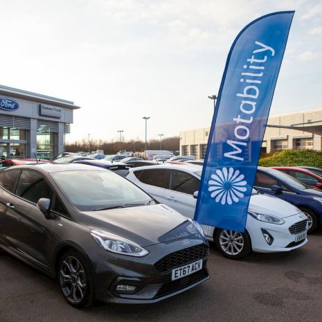 Cars outside a dealership, with a Motability Scheme banner above