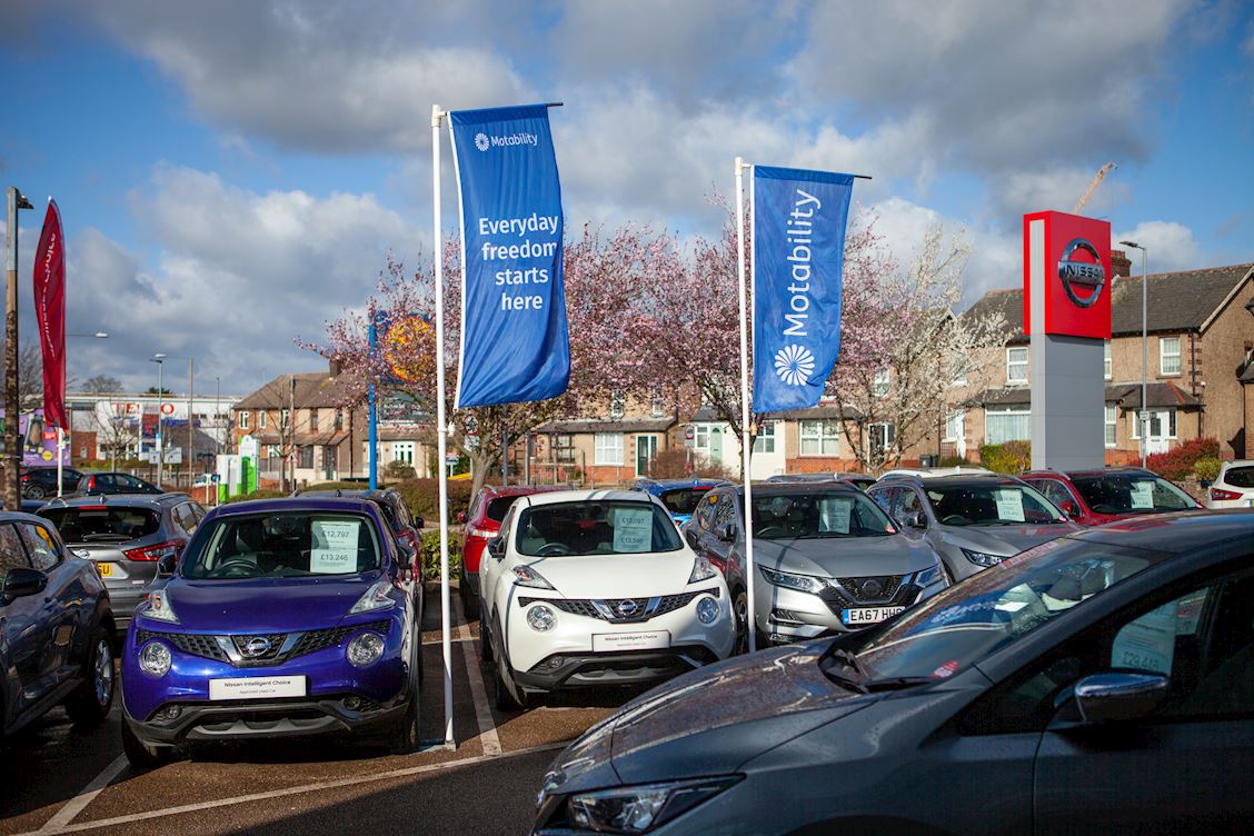 Cars outside a dealership, with Motability Scheme banners above