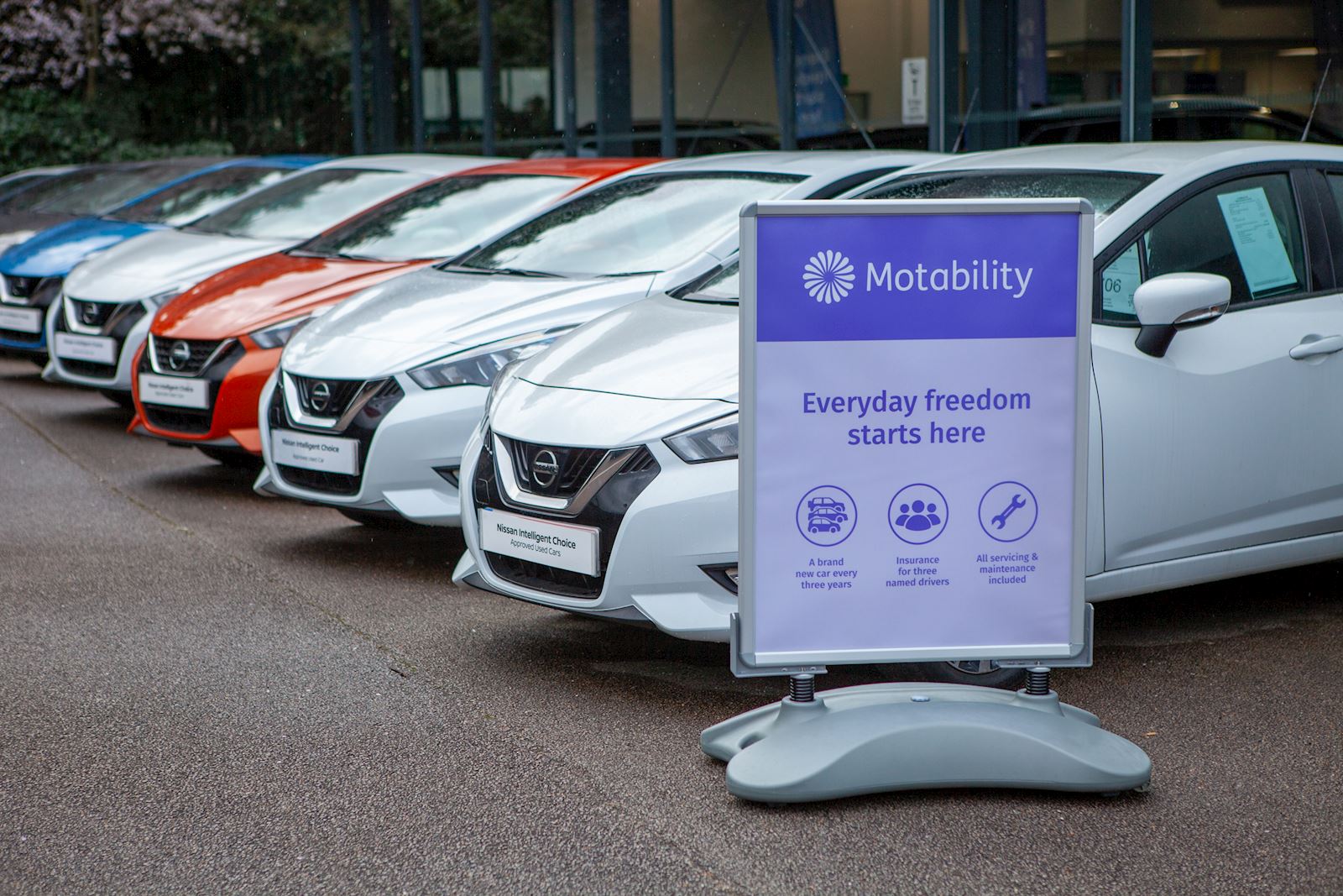 Cars outside a dealership, with a Motability Scheme sign