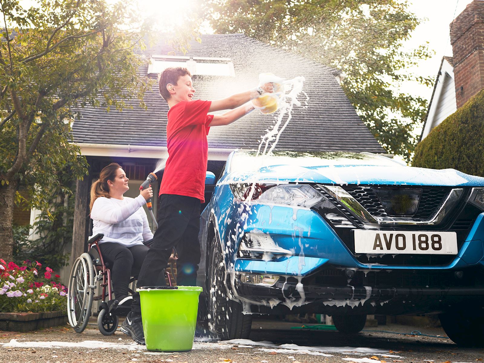A lady with a boy washing the car