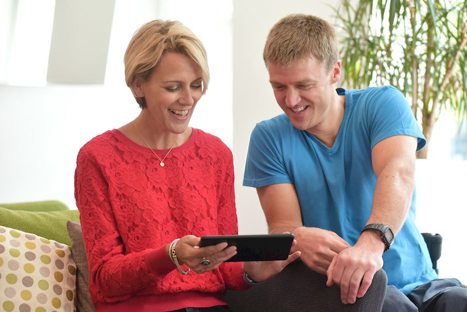 A woman and a man smiling and looking at a tablet