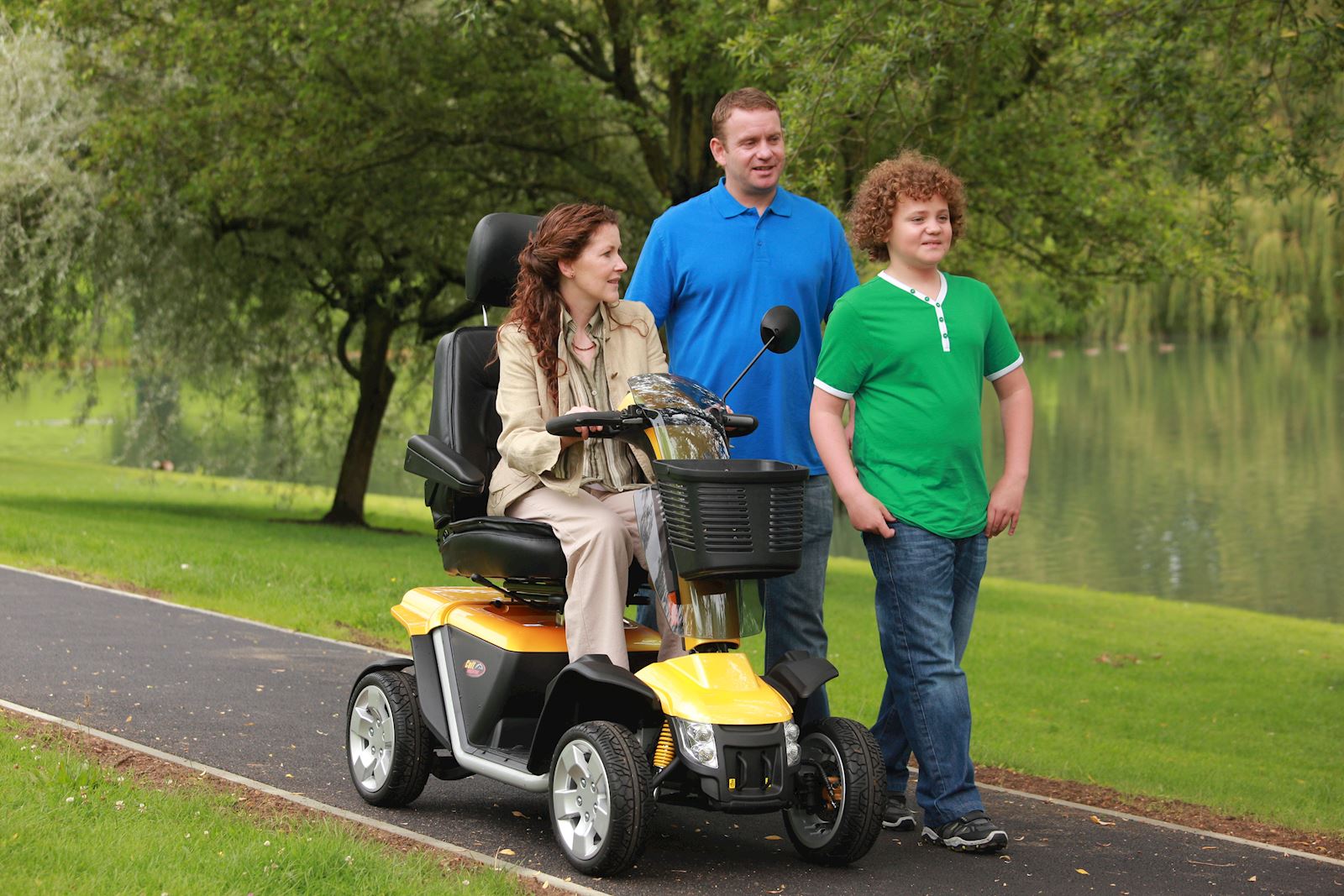 A woman riding a mobility scooter with two people walking next to her