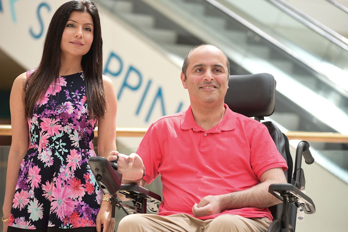 A man in a powered wheelchair, with a woman standing next to him