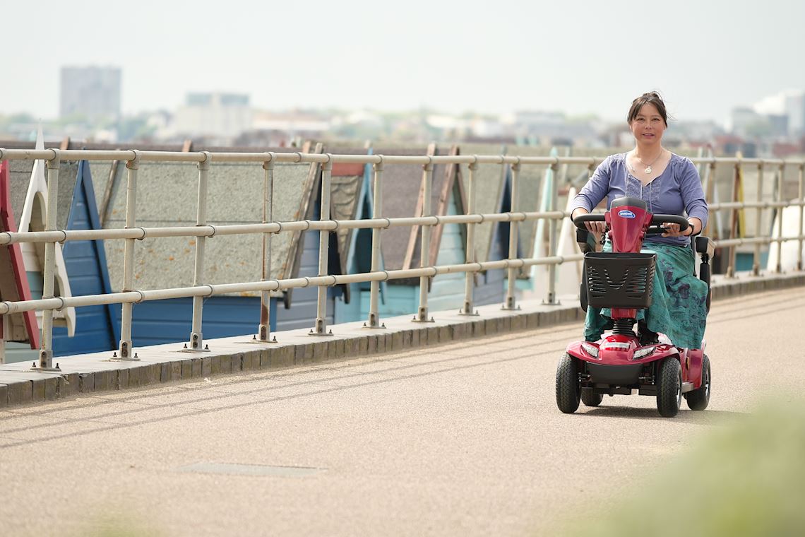 A woman riding a mobility scooter outdoors