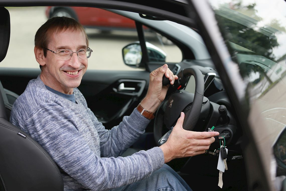 A man smiling while holding a steering ball wheel adaptation