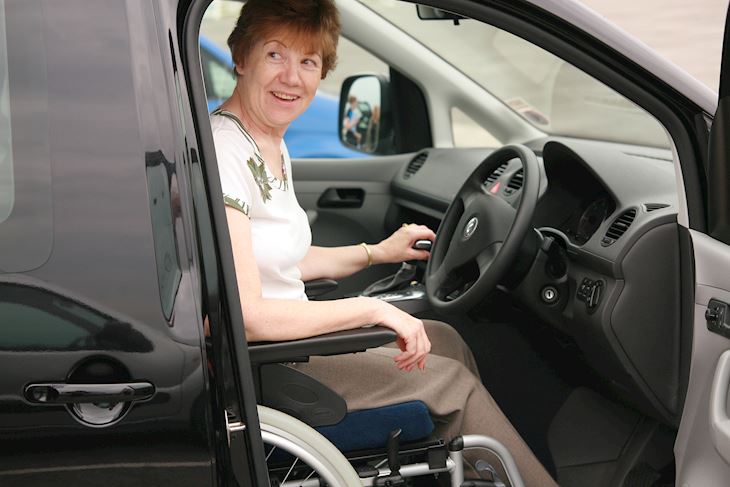A woman sitting in a wheelchair as the driver, in a WAV