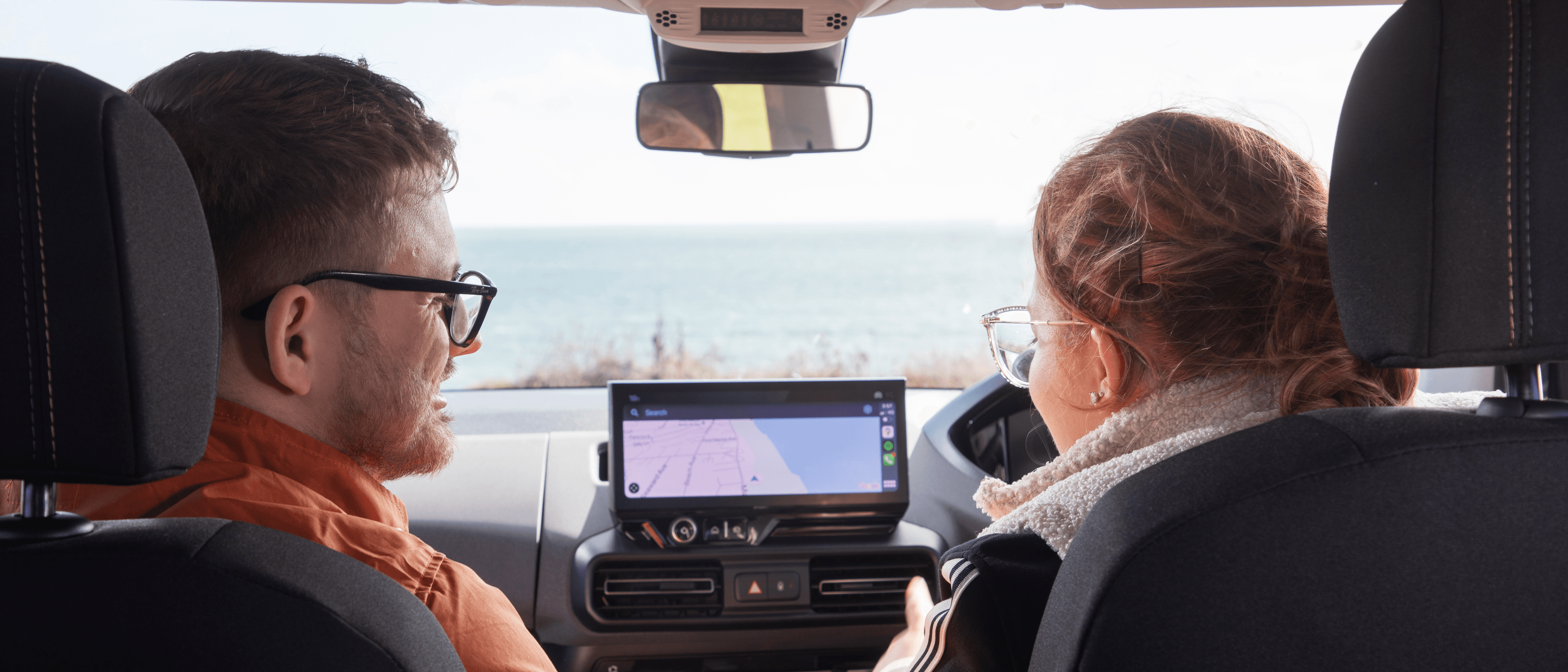 A man and a woman sat in their parked car