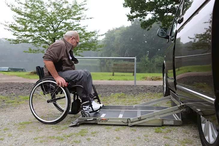 A man in a wheelchair using a lift to get into a WAV