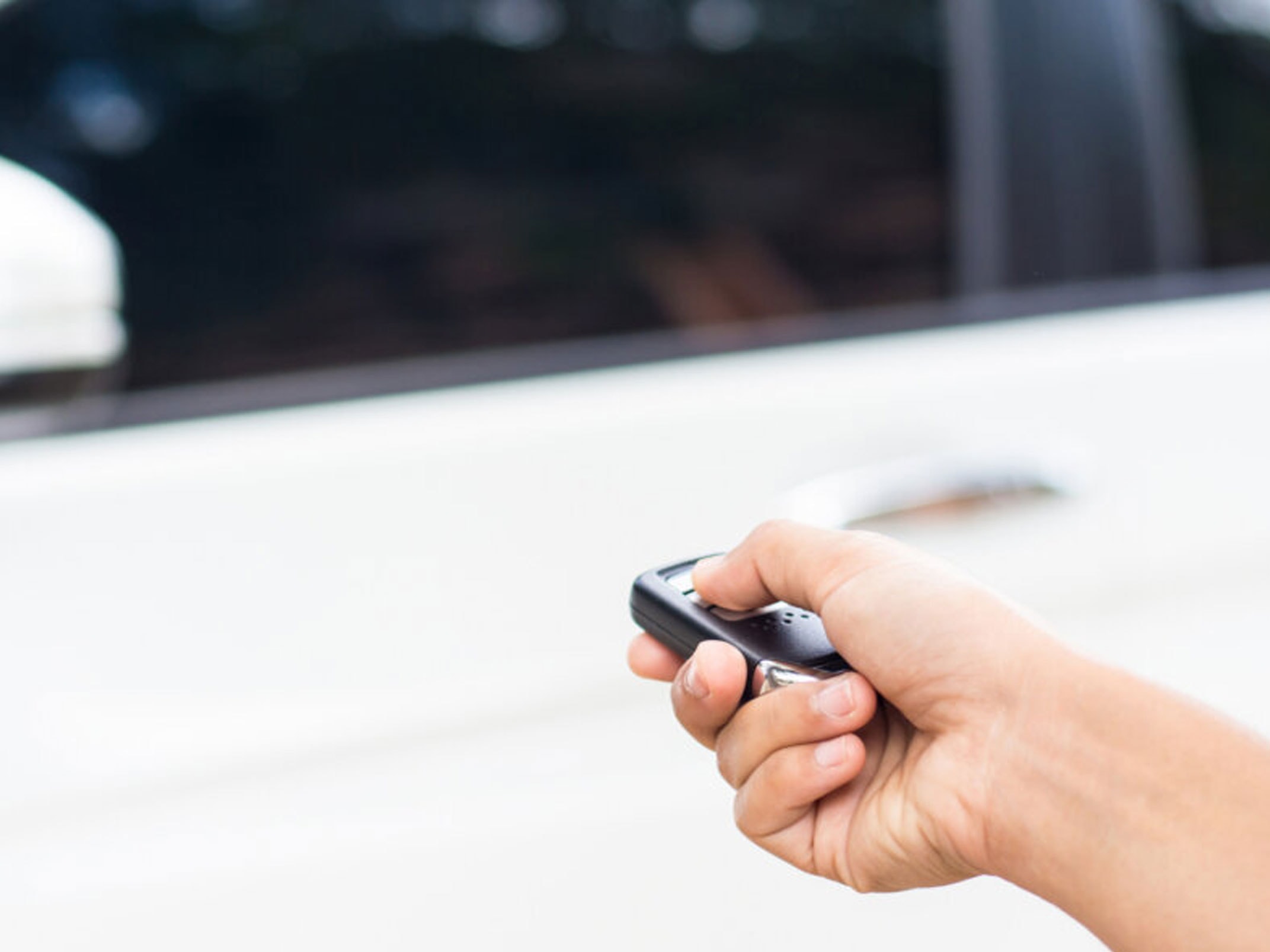 person holding car key to unlock door