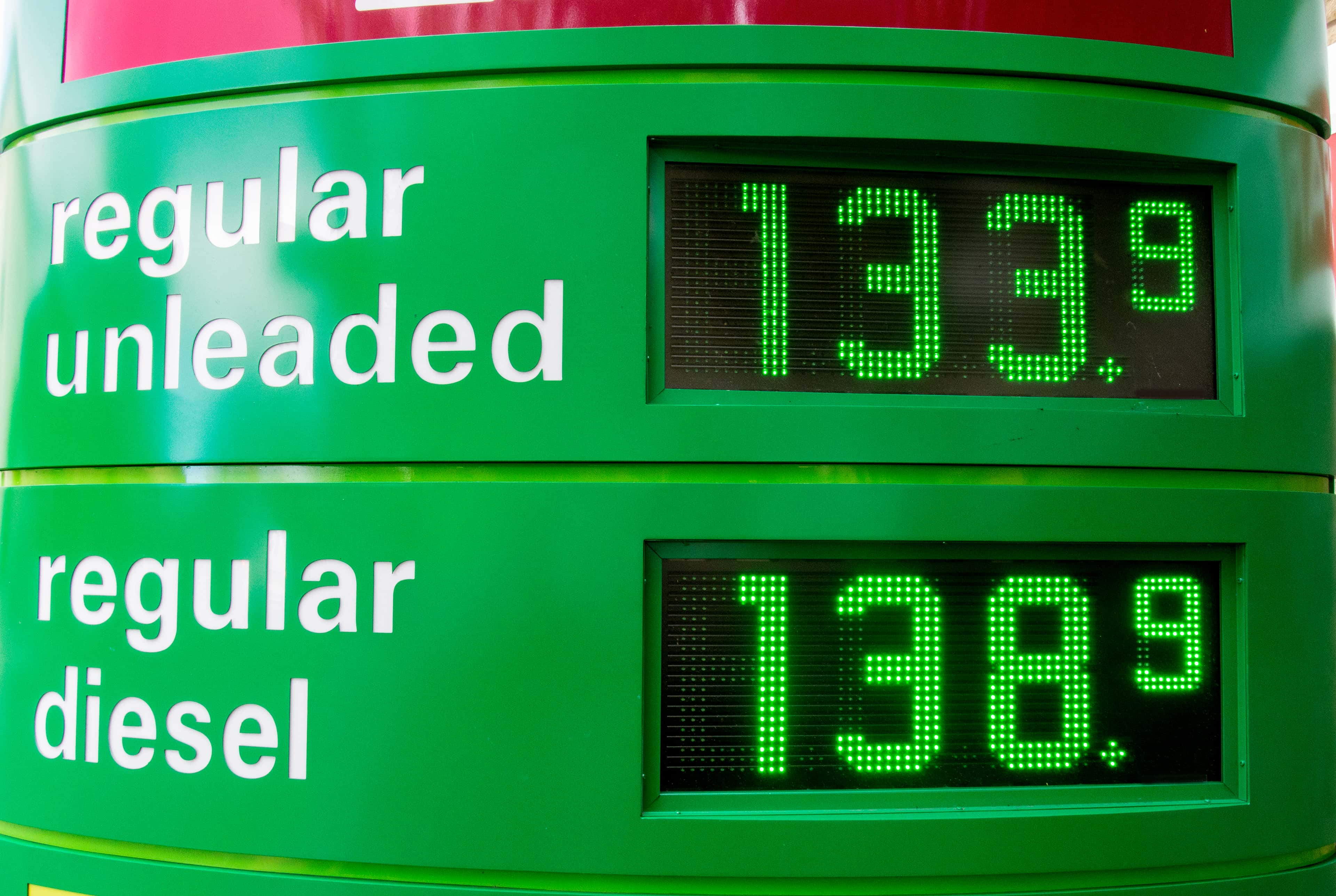 A green digital fuel price display at a petrol station shows regular unleaded at 133.9 and regular diesel at 138.9.