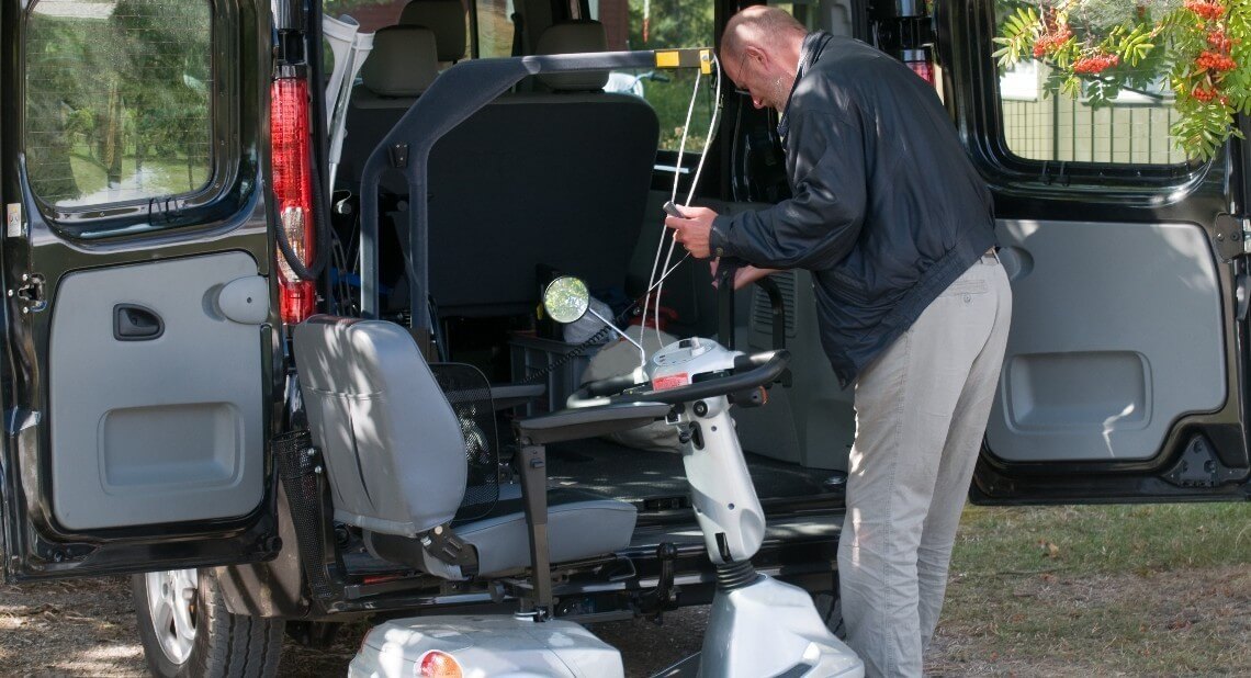 Man using a car hoist to get his mobility scooter inside the car