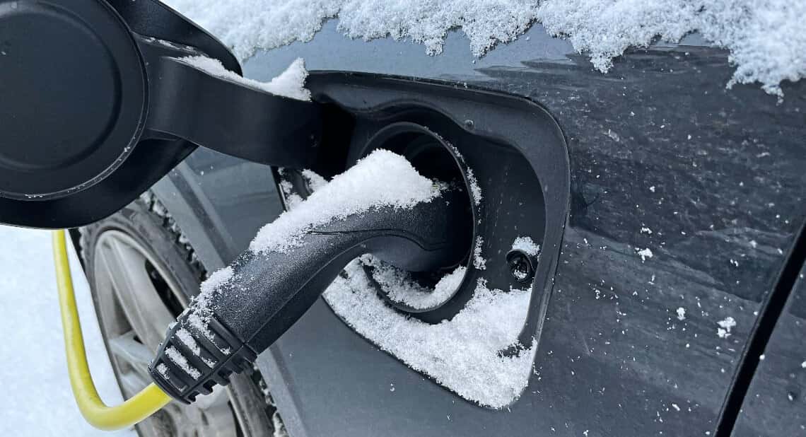 A close-up picture of an Electric Car being charged covered in snow.