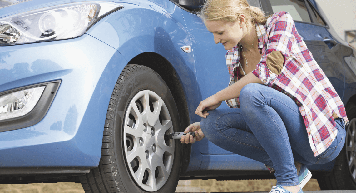 Woman checking tyre pressure on car